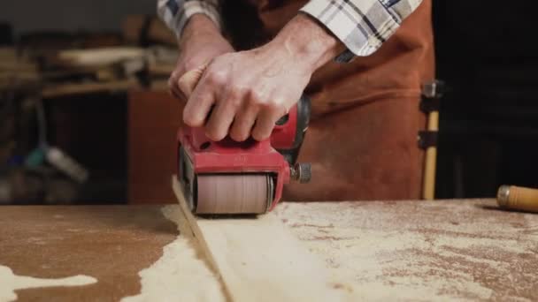 Tischler schleift Holz mit Bandschleifer in der Werkstatt im Holzbrettprojekt oder in der Schreinerei — Stockvideo