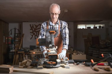 Marangoz marangozluk atölyesinde elektrikli testere makinesiyle tahta kesiyor. Workwood DIY konsepti
