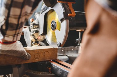 Marangoz marangozluk atölyesinde elektrikli testere makinesiyle tahta kesiyor. Workwood DIY konsepti