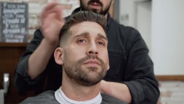 Friseurladen. Mann im Friseurstuhl, Friseur frisiert sich die Haare — Stockvideo