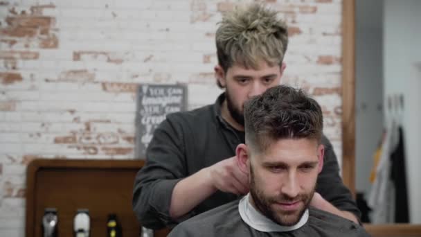 Ο άνθρωπος κουρέας κοπής μαλλιά αρσενικό πελάτη με clipper στο κουρείο. Διαδικασία κομμωτικής. Αργή κίνηση, κοντινό πλάνο — Αρχείο Βίντεο