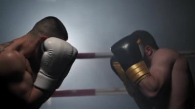 İki profesyonel kaslı, üstsüz erkek boksörün boks ringinde dövüştüğü yavaş çekim..