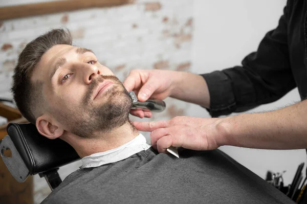Professionele kapper snijden baard van knappe man — Stockfoto