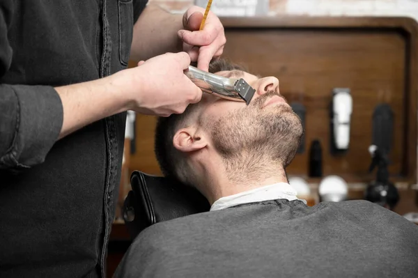 Профессиональный парикмахер стрижет бороду красивого мужчины — стоковое фото