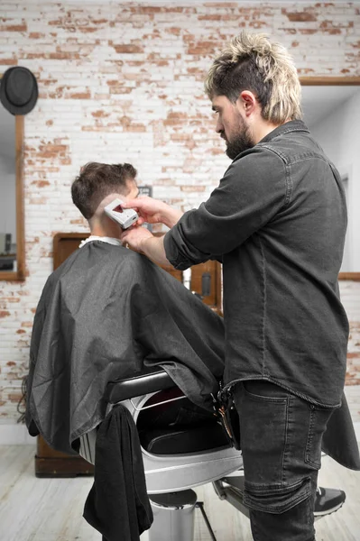 Man kapper knippen haar van mannelijke cliënt met tondeuse in kapperszaak. Haarstyling proces. — Stockfoto