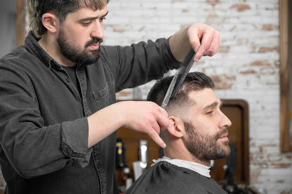 理发师用剪刀剪头发给一个英俊的年轻人 . — 图库照片