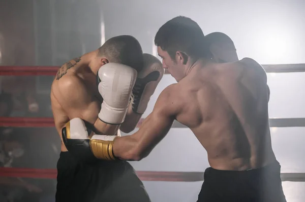 Two professional young muscular shirtless male boxers fighting in a boxing ring. — Stock Photo, Image