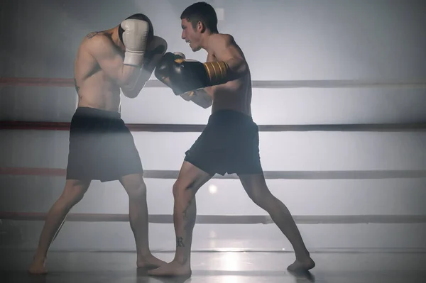 Two professional young muscular shirtless male boxers fighting in a boxing ring. — Stock Photo, Image