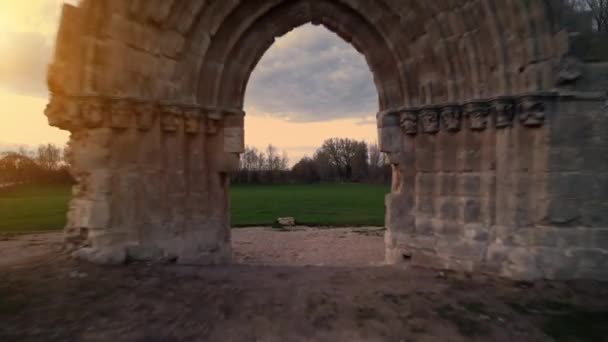 Drone volant à travers une arche médiévale pour révéler un paysage de prairie pittoresque au crépuscule à Sasamon, Castille et Léon, Espagne. — Video