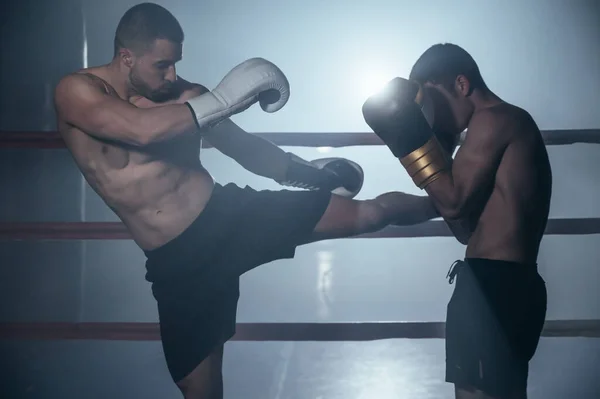 Deux hommes musclés torse nu combattant Kick boxing combat dans le ring de boxe. — Photo