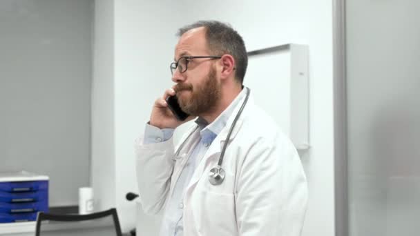 Doctor en el consultorio hablando por teléfono — Vídeo de stock