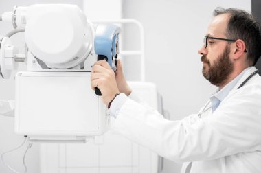 Doktor radyoloji bölümünde röntgen cihazı kullanıyor.
