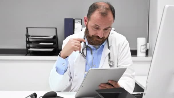 Thoughtful male doctor using digital tablet thinking of medical problem solution. — Vídeo de stock