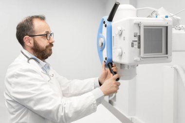 Doktor radyoloji bölümünde röntgen cihazı kullanıyor.