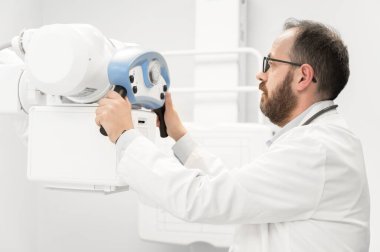 Doktor radyoloji bölümünde röntgen cihazı kullanıyor.