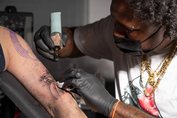 Fotografía cinematográfica de un artista del tatuaje creando arte corporal en el estudio de tatuajes — Foto de Stock