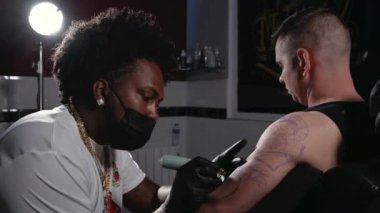 Dövme stüdyosunda vücut sanatı yaratan bir dövmecinin sinematik çekimi.