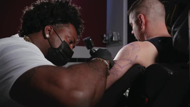 Fotografia cinematográfica de um artista de tatuagem criando arte corporal no estúdio de tatuagem — Vídeo de Stock