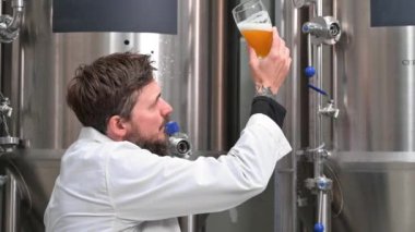 Bira imalathanesinde çalışırken bira fermantasyonunu kontrol eden beyaz önlük giyen Brewer..