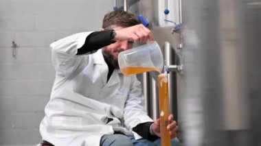 Bira fabrikasında bira üretim sürecini kontrol eden profesyonel bira ustası, içecek yoğunluğunu hidrometreyle ölçüyor.