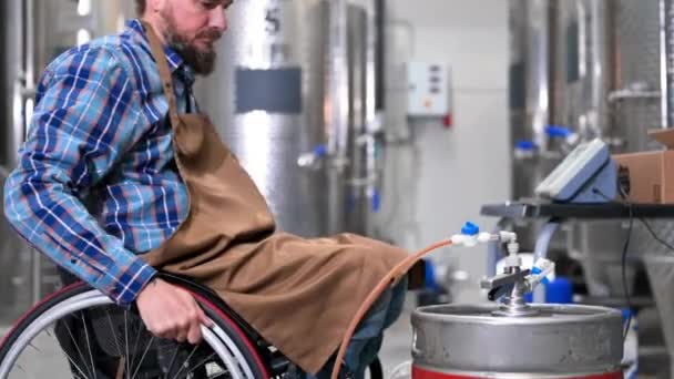 Человек с ограниченными возможностями, использующий инвалидное кресло, работающее на ремесленном пивоваренном заводе. — стоковое видео