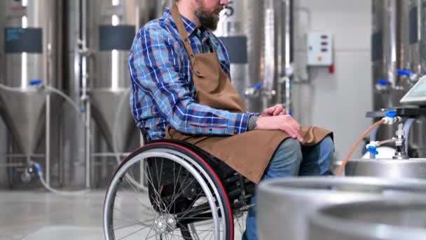 Muž na kolečkovém křesle pracující v pivovarské továrně. — Stock video
