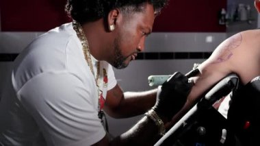 Dövme stüdyosunda vücut sanatı yapan bir dövmecinin yavaş çekim filmi.