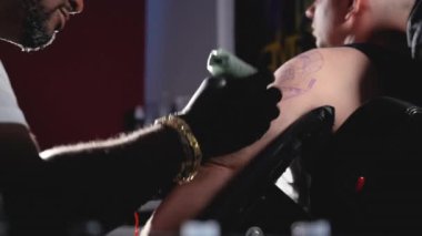 Dövme stüdyosunda vücut sanatı yapan bir dövmecinin yavaş çekim filmi.