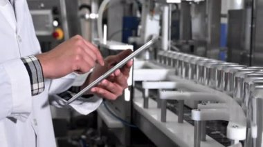 Erkek işçi, içecek fabrikası üretim hattında konserve kutularıyla taşımacılık yapan bir tablette çalışıyor. Kapatın..