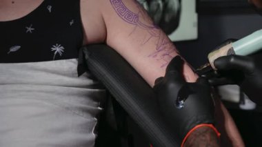 Profesyonel dövme sanatçısı genç bir adamın kolunda dövme yapıyor..