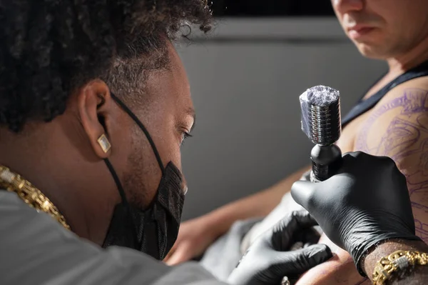 Fotografía cinematográfica de un artista del tatuaje creando arte corporal en el estudio de tatuajes — Foto de Stock