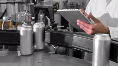 Quality Supervisor or Technician is Inspecting the Automated Production at a beverage Factory. Close Up Shot of Employee Using Tablet Computer for Work.