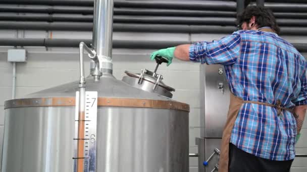 Человек, работающий на пивоваренном заводе, открывает один из цехов — стоковое видео
