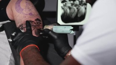 Dövme stüdyosunda vücut sanatı yapan bir dövmecinin yavaş çekim filmi. Yüksek kalite Tam HD görüntü