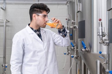 Bira imalathanesinde çalışırken bira fermantasyonunu kontrol eden beyaz önlük giyen Brewer. Yüksek kaliteli fotoğrafçılık