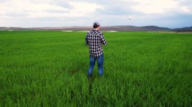 Genç çiftçi bir tarlanın üzerinde dron uçuruyor. Yüksek kalite 4k görüntü