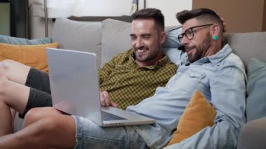 Male caucasian gay couple using laptop computer at home. High quality 4k footage