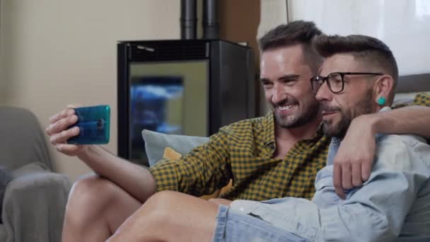 Gay Couple Sitting Sofa Home Making Video Call Mobile Phone — Stockvideo