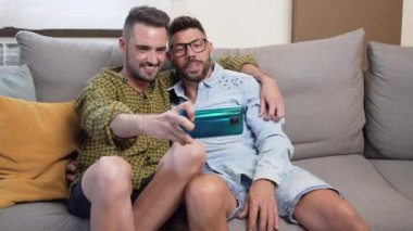Young smiling gay couple taking selfie at home. High quality 4k footage