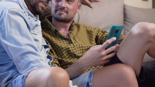 Щаслива Молода Пара Гей Використовуючи Мобільний Телефон Сидячи Дивані Вітальні — стокове відео