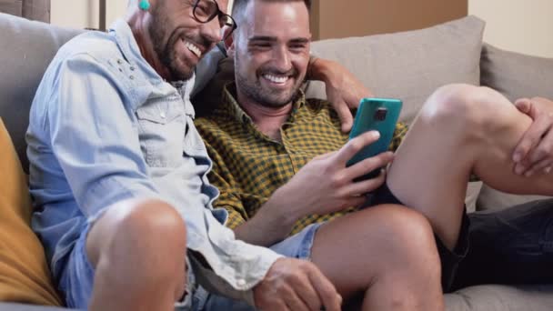 Весела Гомосексуальна Пара Сидить Дивані Обіймається Дивиться Мобільний Телефон Дивиться — стокове відео