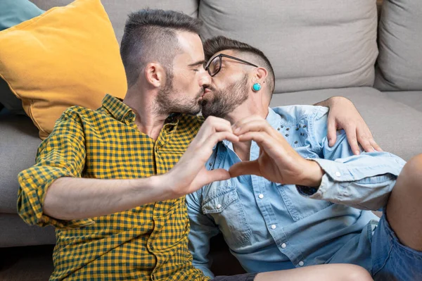 Young Gay Couple Kissing While Doing Heart Symbol Hands Home — Foto Stock