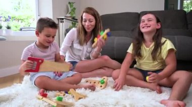 Mother and children playing together with colorful construction toys on a carpet on the floor. High quality 4k footage
