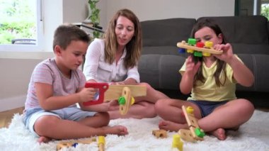 Mother and children playing together with colorful construction toys on a carpet on the floor. High quality 4k footage