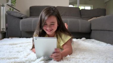 Adorable little girl using a digital tablet on the floor at home. High quality 4k footage