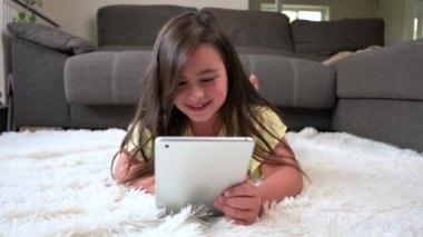 Adorable little girl using a digital tablet on the floor at home. High quality 4k footage