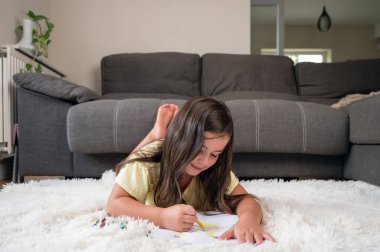 Yerde uzanmış çizim yapan neşeli küçük kız. Yüksek kaliteli fotoğrafçılık