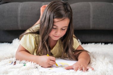 Yerde uzanmış çizim yapan neşeli küçük kız. Yüksek kaliteli fotoğrafçılık