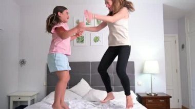 Aile eğlencesi. Anne ve kızı yatakta zıplıyorlar. Yüksek kalite 4k görüntü