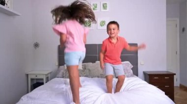 Yatakta zıplayan neşeli kardeşler. Yüksek kalite 4k görüntü